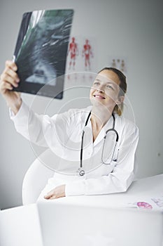 Pretty young doctor looking at x-rays in her doctor`s office