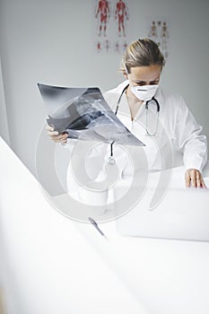 Pretty young doctor looking at x-rays in her doctor`s office