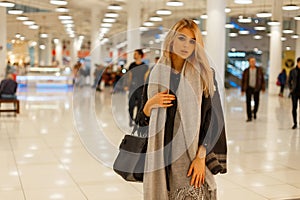 Pretty young elegant blonde with beautiful eyes in a vintage stylish coat with a gray fashionable scarf