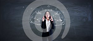 Pretty young european businesswoman with crossed fingers standing on chalkboard wall background with drawn muscle hands. Strength