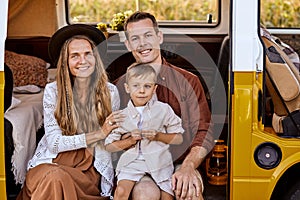 Pretty young european couple with son, travelers on road trip on yellow retro van