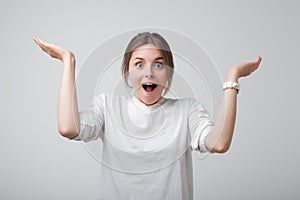 Pretty young european woman in white t-shirt is excited and happy to know good news.