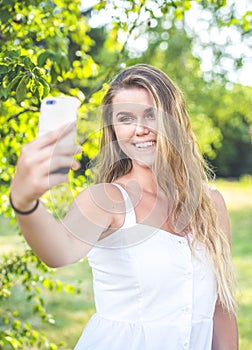 Pretty young female with big smile are taking selfie oudoor.