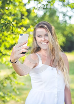 Pretty young female with big smile are taking selfie oudoor.