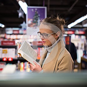 Pretty, young female choosing a good book to buy