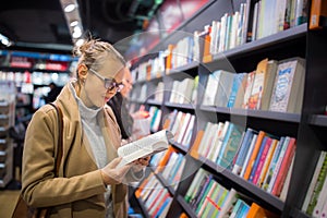 Pretty, young female choosing a good book to buy photo