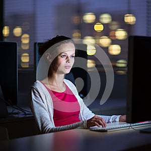 Pretty, young female college student using a desktop computer/pc in a college library