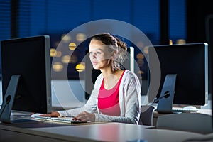 Pretty, young female college student using a desktop computer/pc in a college library (shallow DOF; color toned image)