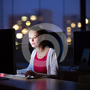 Pretty, young female college student using a desktop computer/pc in a college library (shallow DOF; color toned image)