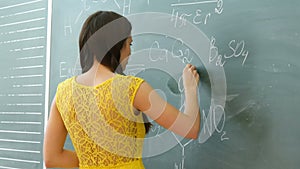 Pretty young female college student writing on the chalkboard blackboard during a chemistry class