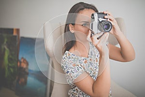 Pretty, young female photographer in her studio taking photos with a vintage film camera