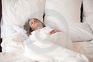 Pretty young female sleeping well in white cozy bed