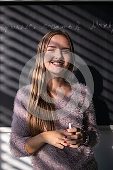 Pretty, young female student in front of a blackboard