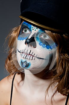 Pretty young female in sugar skull make up and hat