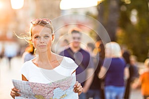 Pretty young female tourist studying a map