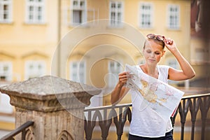 Pretty young female tourist studying a map