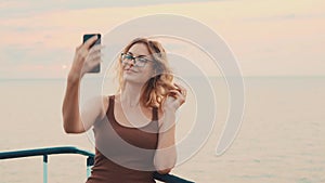 Pretty young girl blogger takes her journey on camera, lady with blond hair and glasses makes selfie for her family