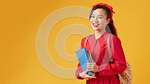 Pretty young girl in casual clothes with backpack posing isolated on yellow background. Education in high school university