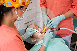 Dental checkup, being given to young girl, by female dentist with assistant