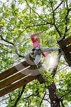 pretty young girl doing tree climbing in a forest park in southwest France