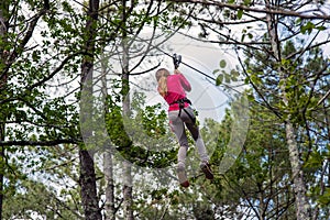 pretty young girl doing tree climbing in a forest park in southwest France