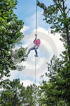 pretty young girl doing tree climbing in a forest park in southwest France