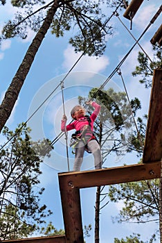 pretty young girl doing tree climbing in a forest park in southwest France