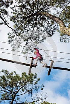 pretty young girl doing tree climbing in a forest park in southwest France