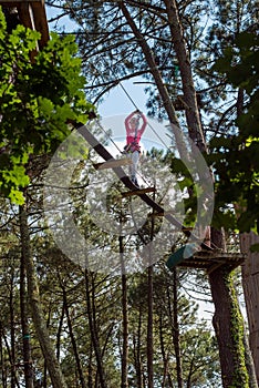 pretty young girl doing tree climbing in a forest park in southwest France