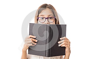 Pretty young girl in glasses hiding behind a black book
