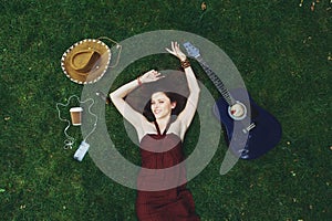 Pretty young girl with guitar lying on grass