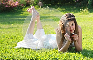 Pretty young girl lying on grass with bare feet