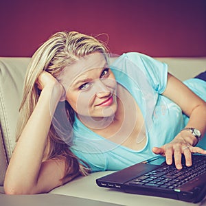 Pretty Young Girl Is Lying on a Sofa and Chating via Laptop