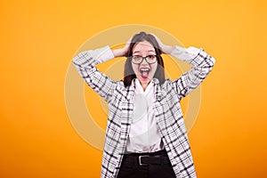 Pretty young girl with modern clothes being schocked in studio over yellow background