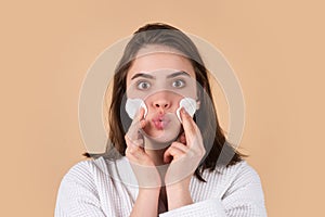 Pretty young girl with daily morning skincare procedures, cleansing face skin with natural lotion tonic using cotton