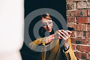 Pretty young girl in olive long coat, hooded sweatshirt. Portrait of woman with hood on dark background