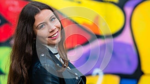 Pretty young girl portrait on blurred wall sprayed with graffiti