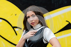 Pretty young girl portrait on blurred wall sprayed with graffiti