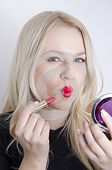 Pretty young girl puckered lips while putting on makeup