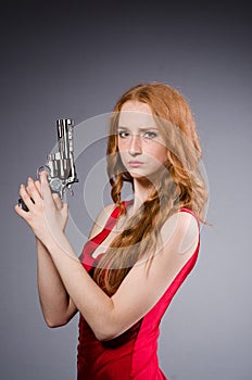 Pretty young girl in red dress with gun isolated