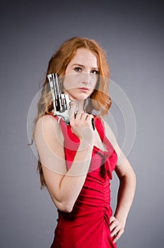 Pretty young girl in red dress with gun isolated