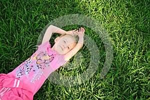 Pretty young girl relaxing on green grass