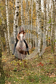 Pretty young girl riding a horse without any equipment in autumn