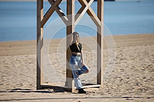 Pretty young girl in ripped jeans and black top and boots. The girl is rebellious and with a tough character. The girl is leaning