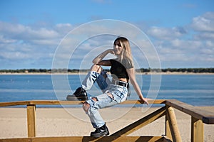 Pretty young girl in ripped jeans and black top and boots. The girl is rebellious and with a tough character. The girl is sitting