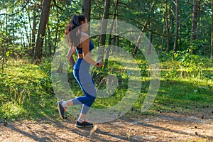 Pretty young girl runner jogging morning in the forest.Young pretty fitness woman running at forest trail