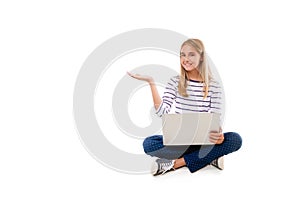 Pretty young girl sitting on the floor with crossed legs and showing something on the palm,isolated