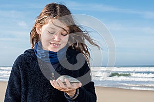 pretty young girl smiling holding in her hand a seashell found on the beach