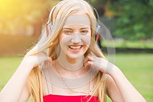 Pretty young girl smiling with pleasure as she listens to music in the garden
