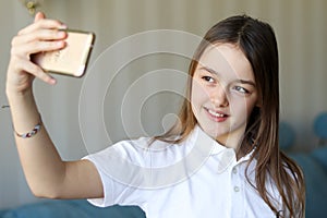 Pretty young girl smiling and taking selfie at home